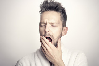 tired man yawning in white tshirt due to tiredness